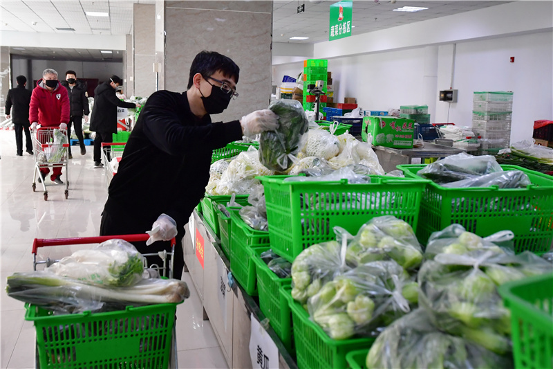 2月16日,在唐山市荷花坑市场分拣中心,工作人员根据居民订单分拣蔬菜.